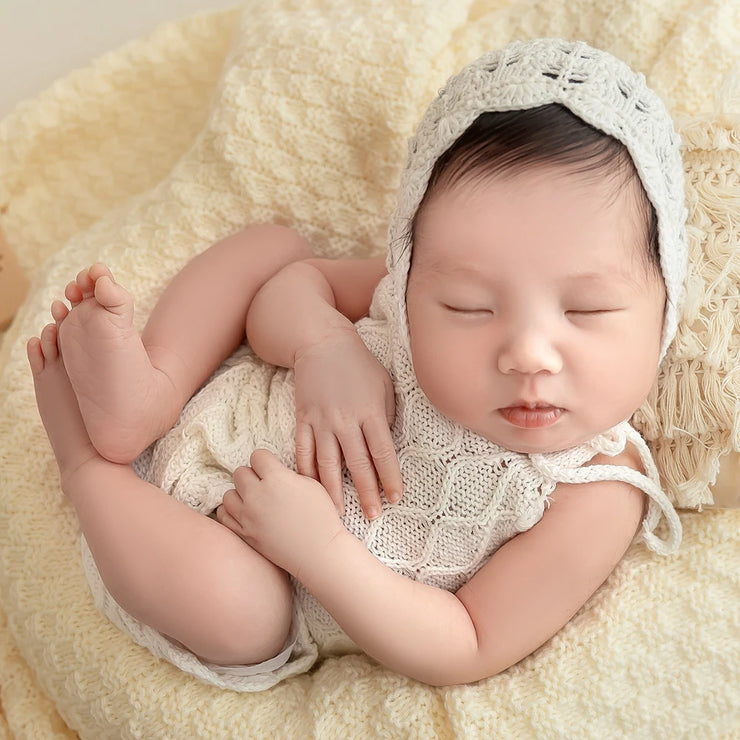 Handcrafted knitted newborn girl outfit, perfect for baby photography with lace details.